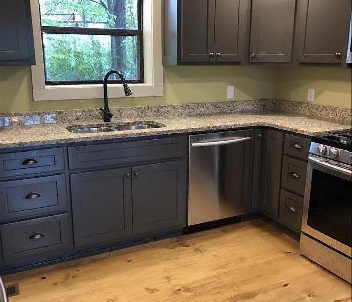 A kitchen with brand new granite countertops, a silver stove, and new brown cabinets.